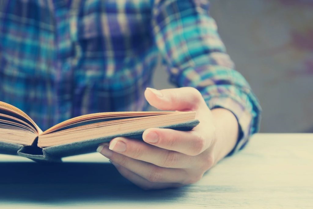 Picture of a man holding a book and reading it.