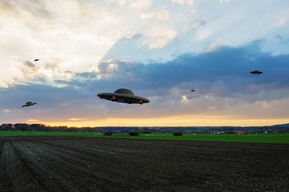 Graphically edited photo of landscape with UFOs flying overhead.