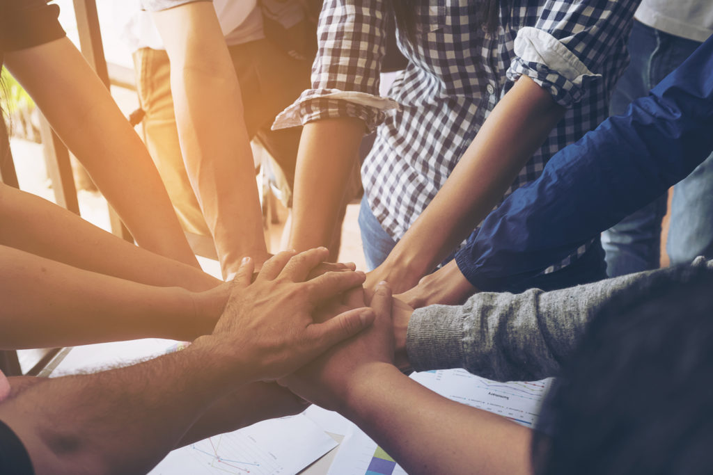 Photo of people with their hands in the center