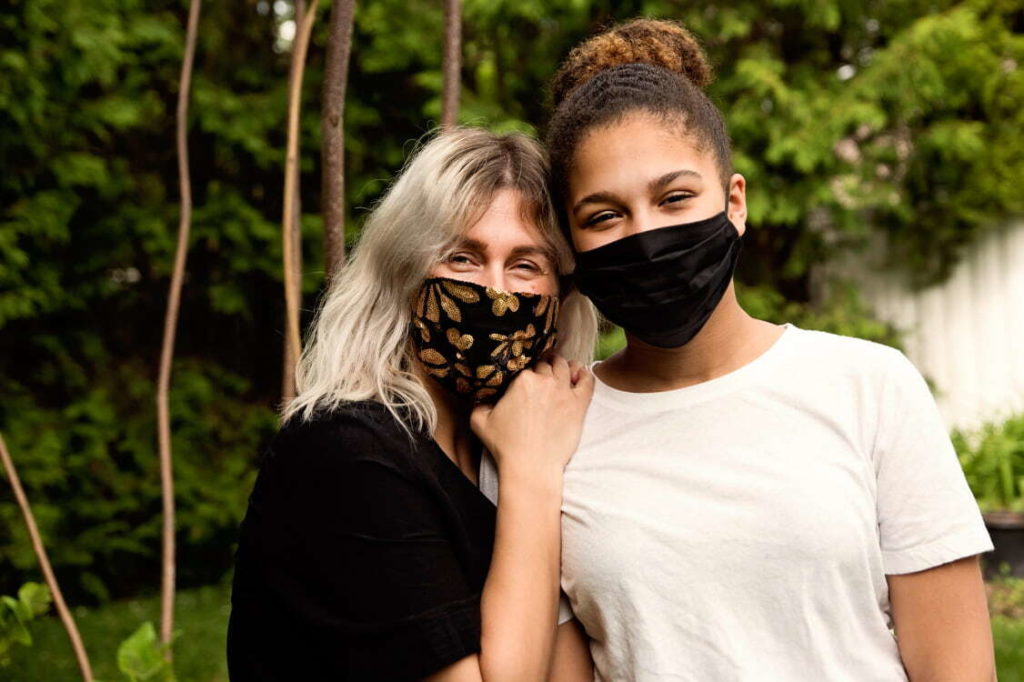 Two women standing outside with masks covering their noses and mouths