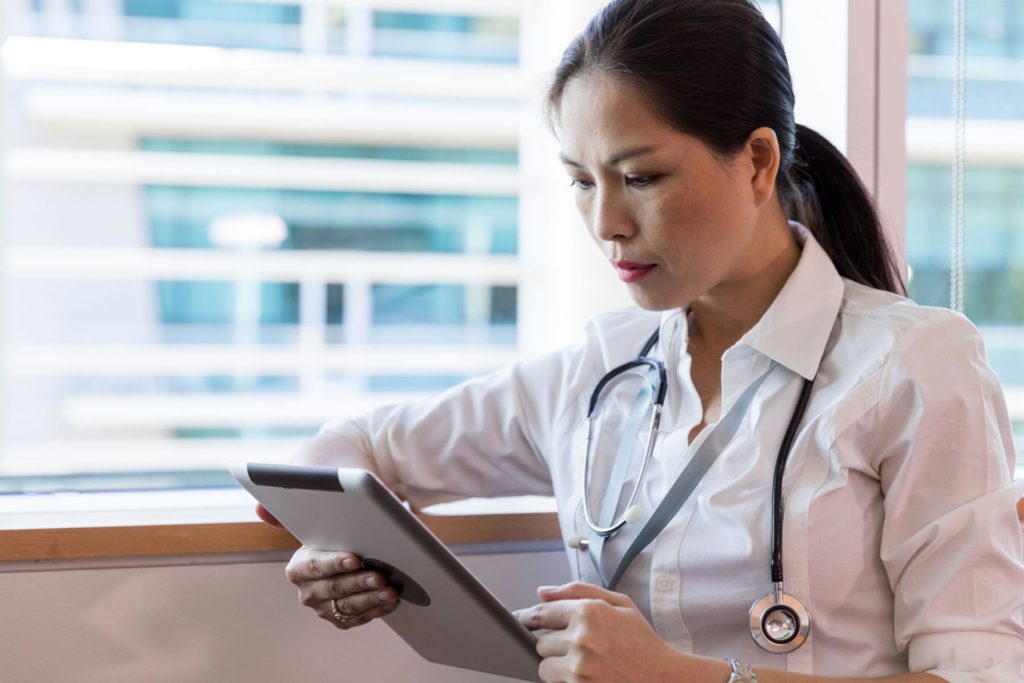 Female doctor looking at tablet in front of window