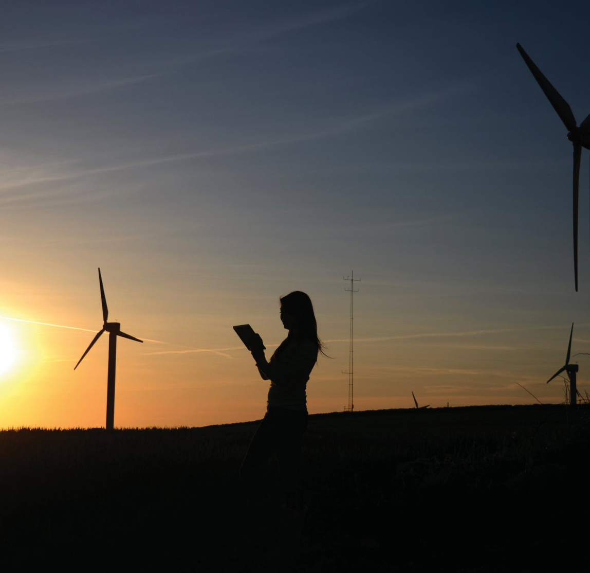 Woman in front of windmills at sunset