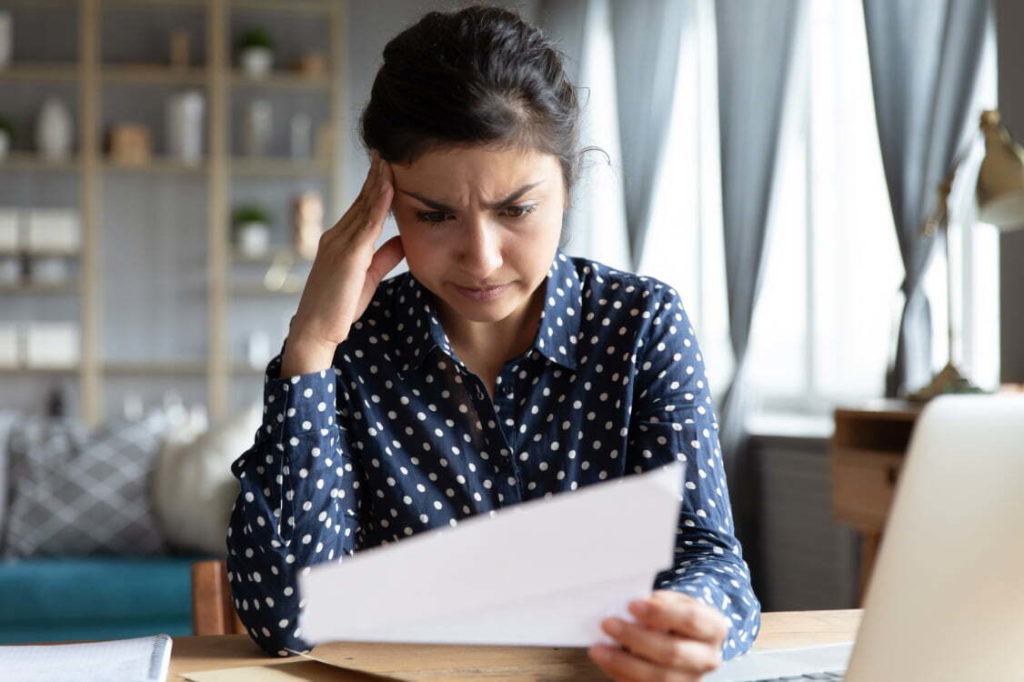 Woman looking confused at paperwork while sitting at a desk