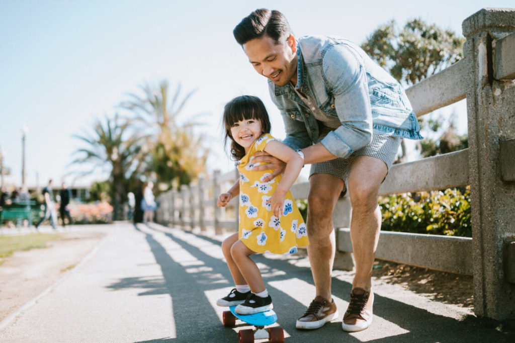 Father guiding daughter on a skateboard