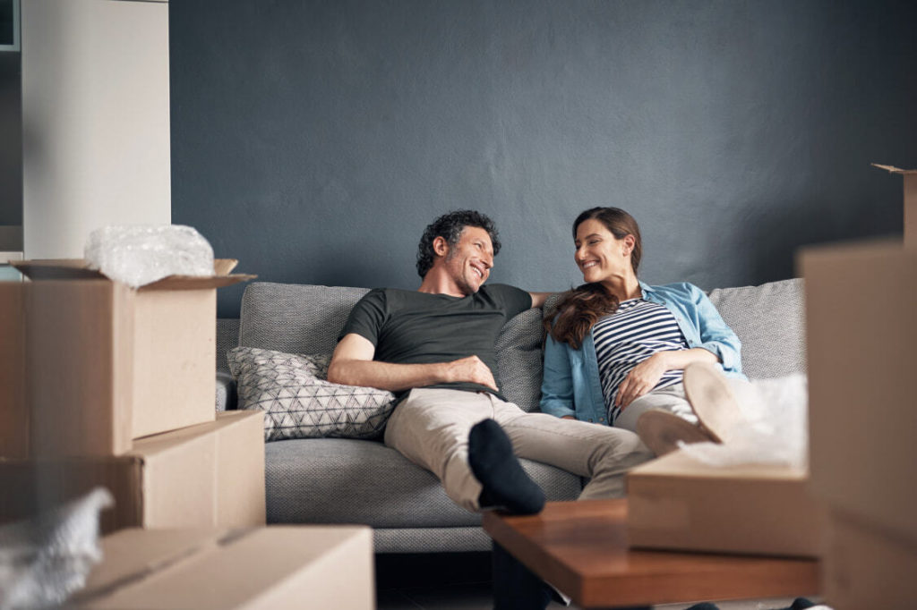 couple relaxing on a couch after moving, boxes all around them