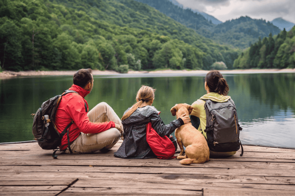 family sitting on a dock of a lake looking off into the distance