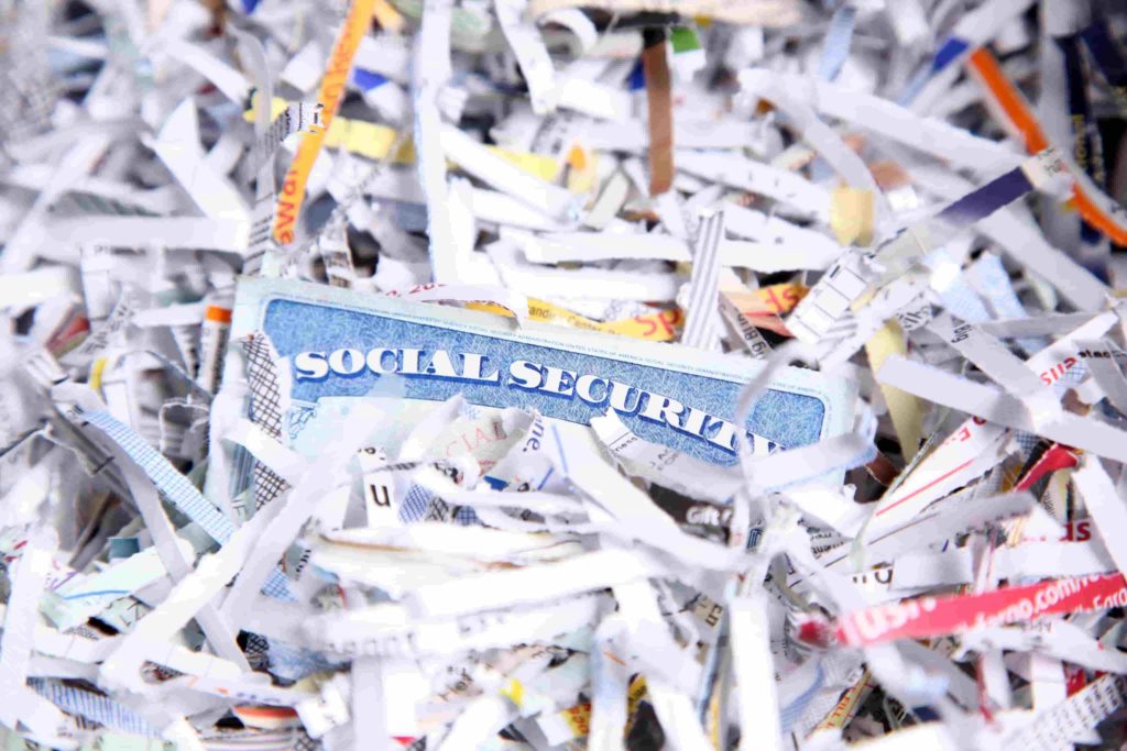 an intact social security card sits amongst shredded paper