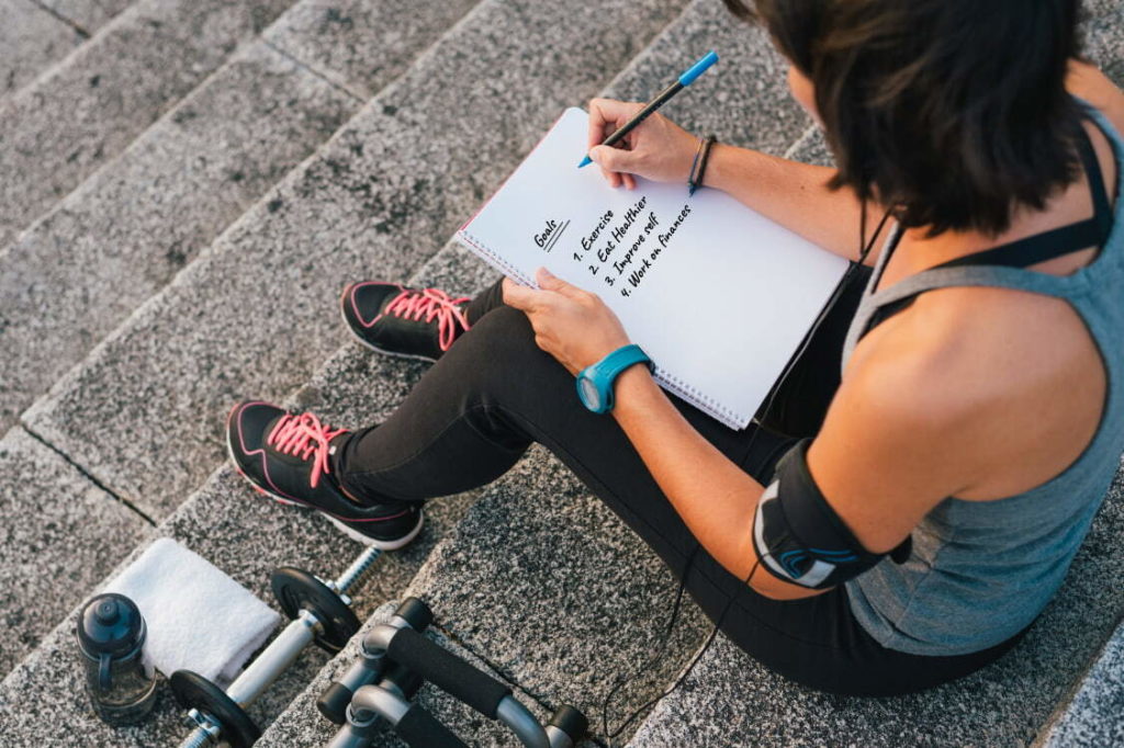 woman sitting on steps writing list of things she wants to improve