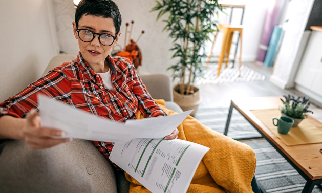 woman reviewing documents sitting on a couch with a blanket on her lap