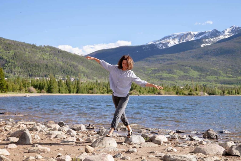 woman walking on rocks on the shore of a mountain lake