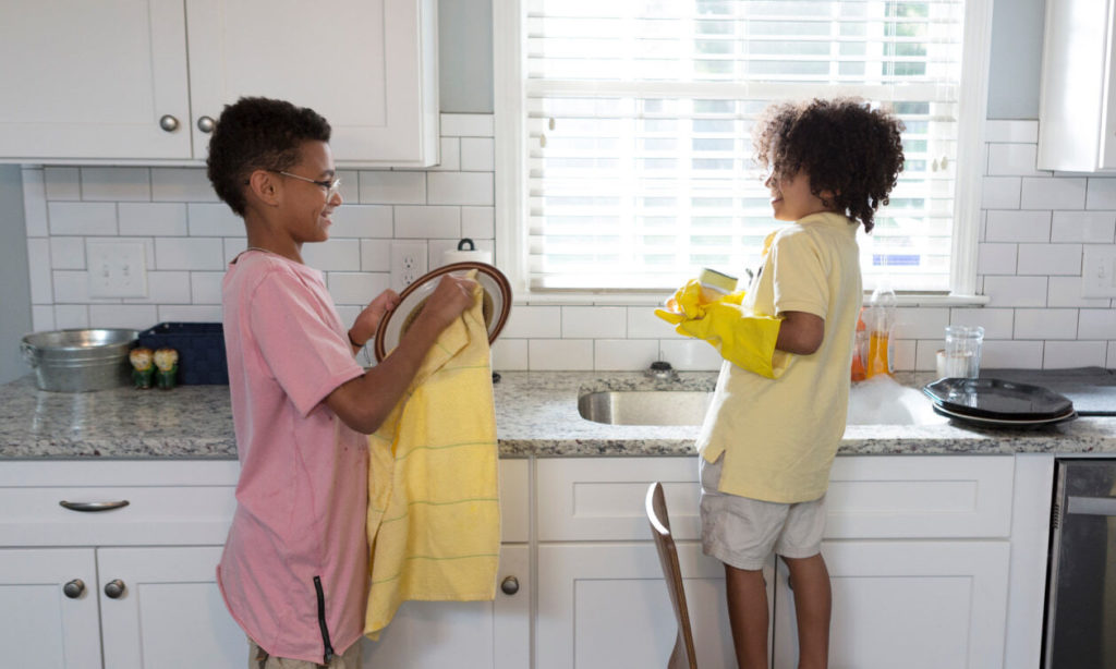 two kids at the sink doing dishes