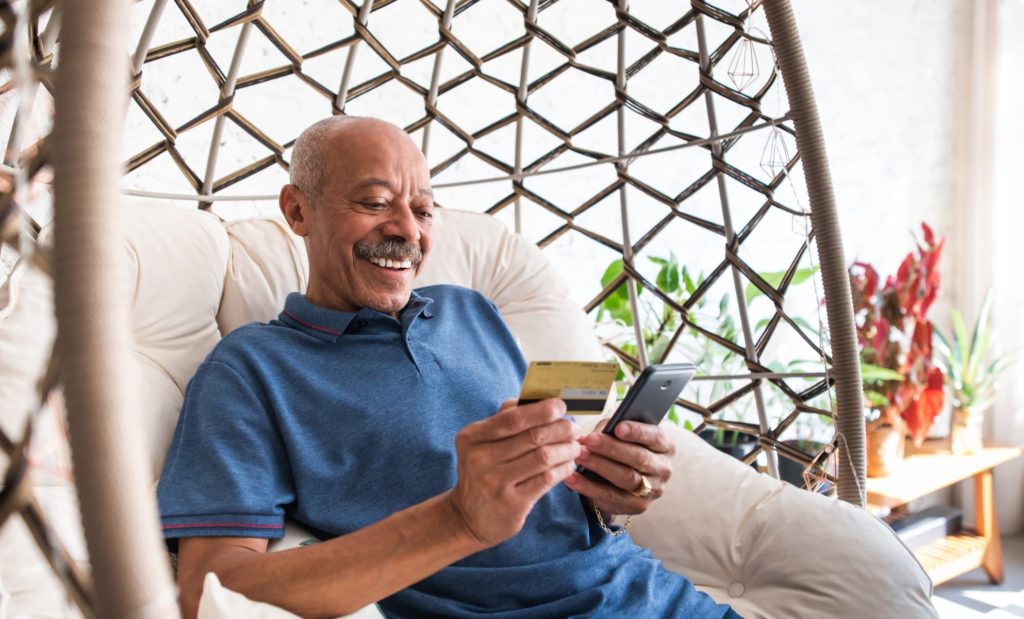 adult senior man using mobile phone and holding credit card in hand