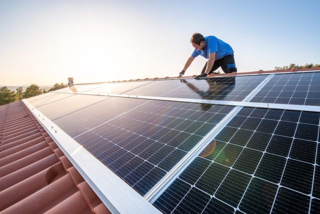 person installing solar panels on a ceramic roof