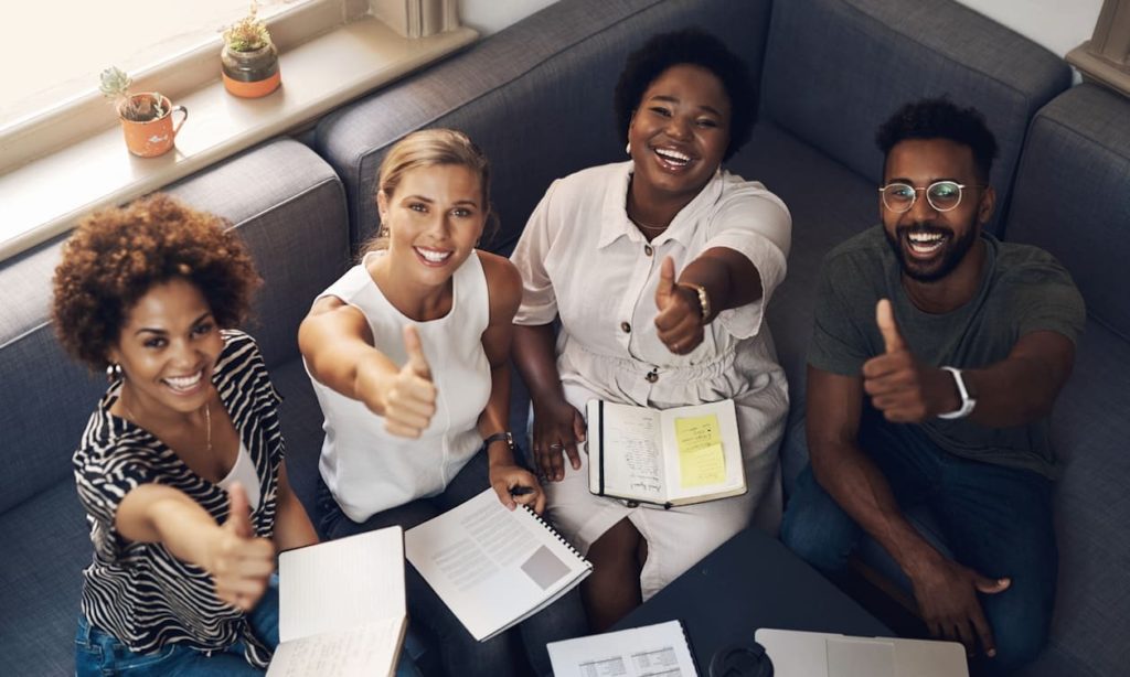 Shot of a group of young businesspeople showing thumbs up during a meeting in a modern office