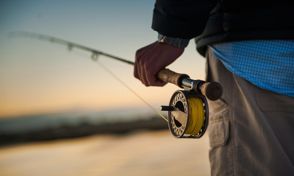 Sunrise over the marsh with man holding a fly rod and reel