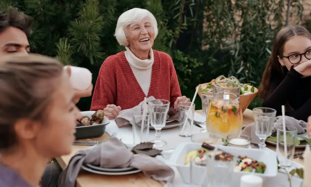 older woman eating outdoors surrounded by family