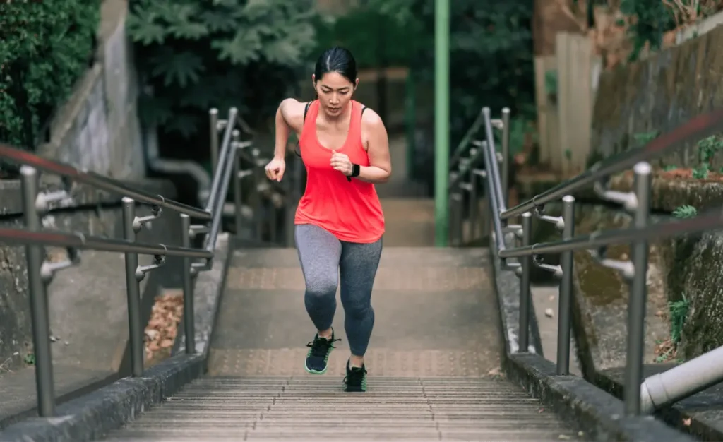 A young female athlete is running up stairs.