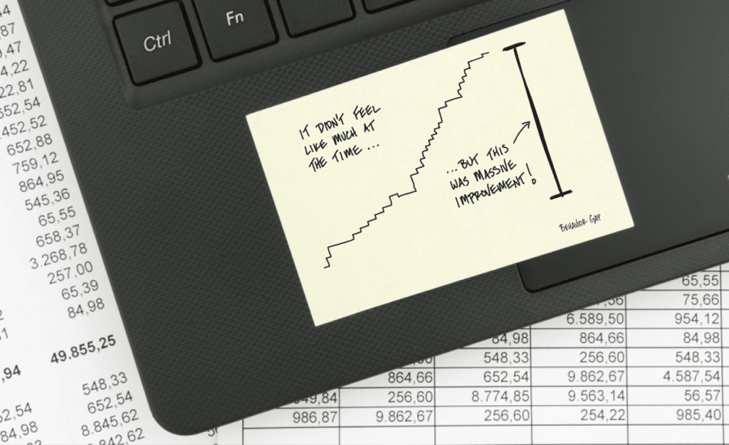 laptop on financial documents that has a sticky note featuring a chart depicting incremental change as stair steps.