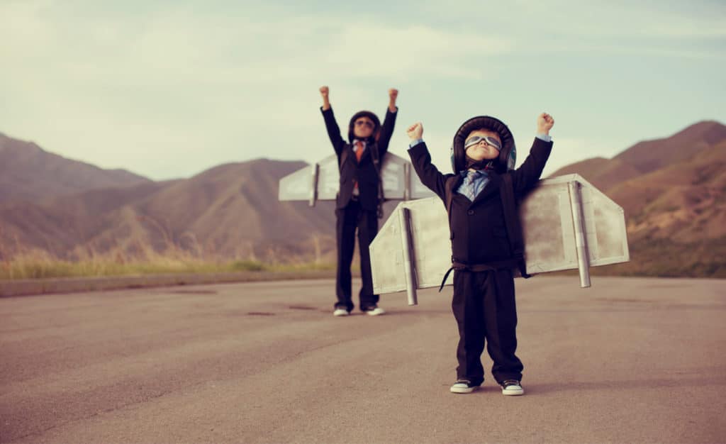 Two young entrepreneurs in suits and wings are getting ready to blast off into the sky.