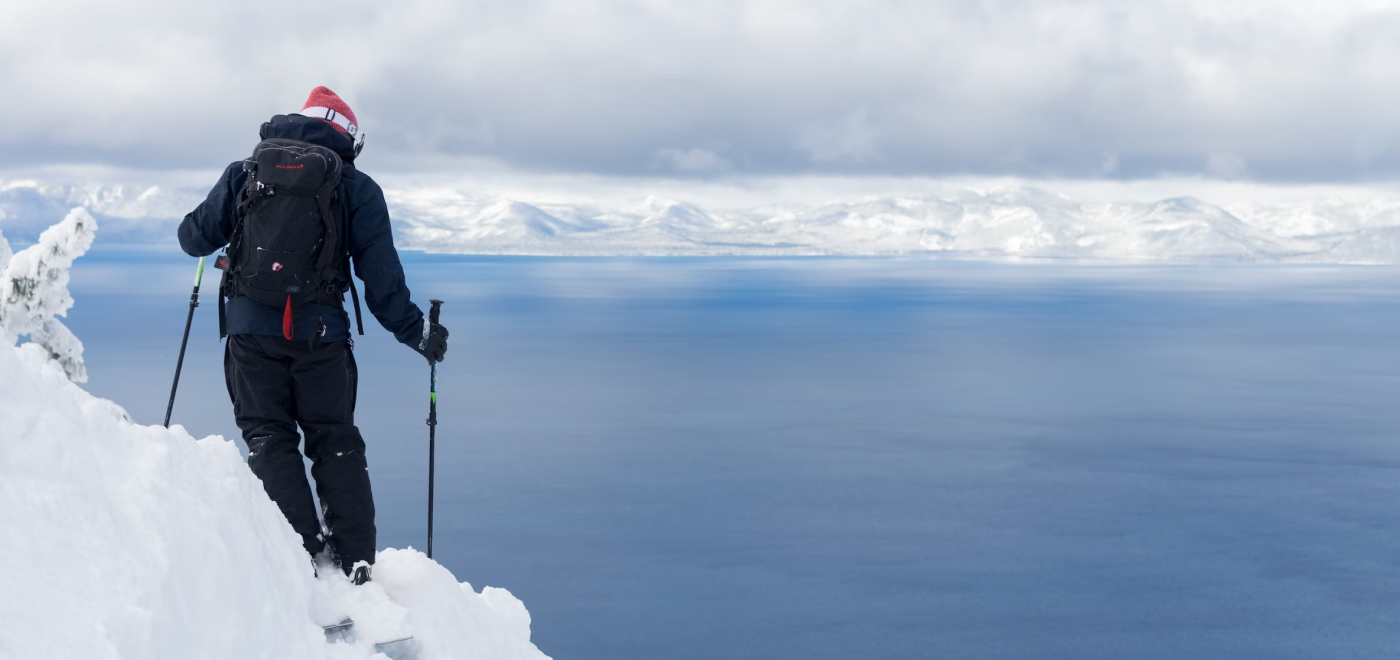 Confident skiier on a high steep slope overlooking blue skies