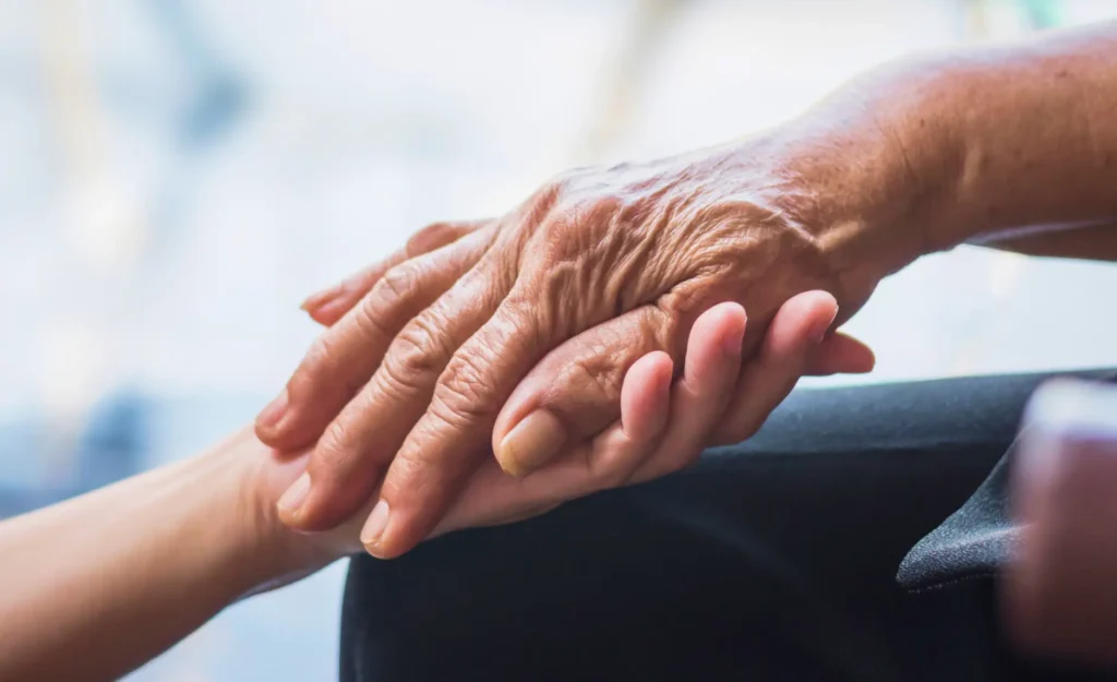 an older hand holding a younger hand