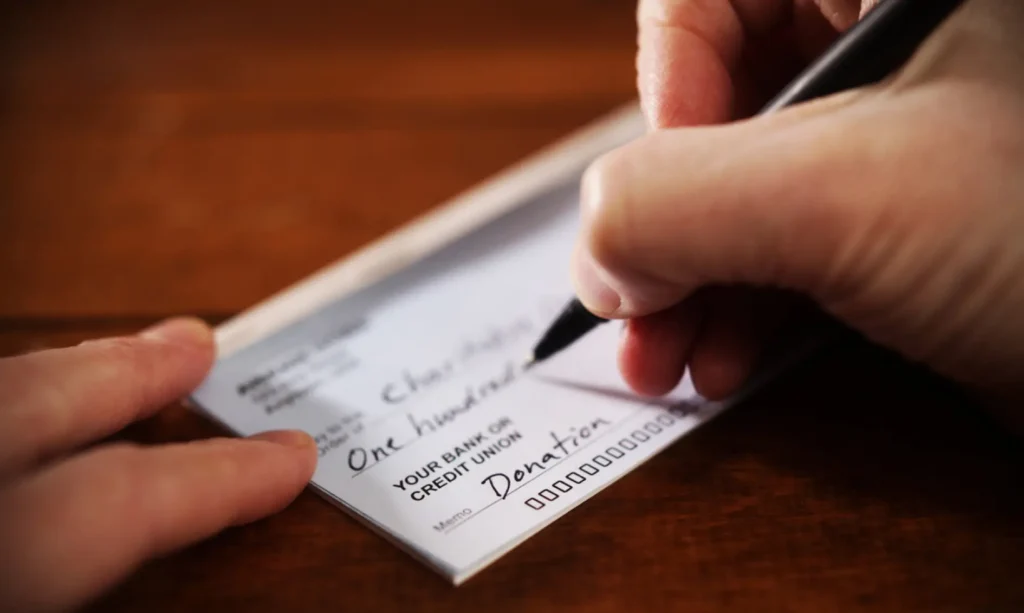 an image of a person's hands writing a check for a charitable contribution