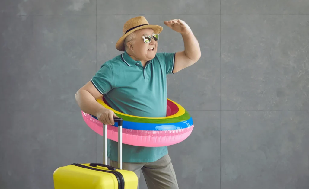 a senior man in an inner tube with a suitcase ready to go on vacation