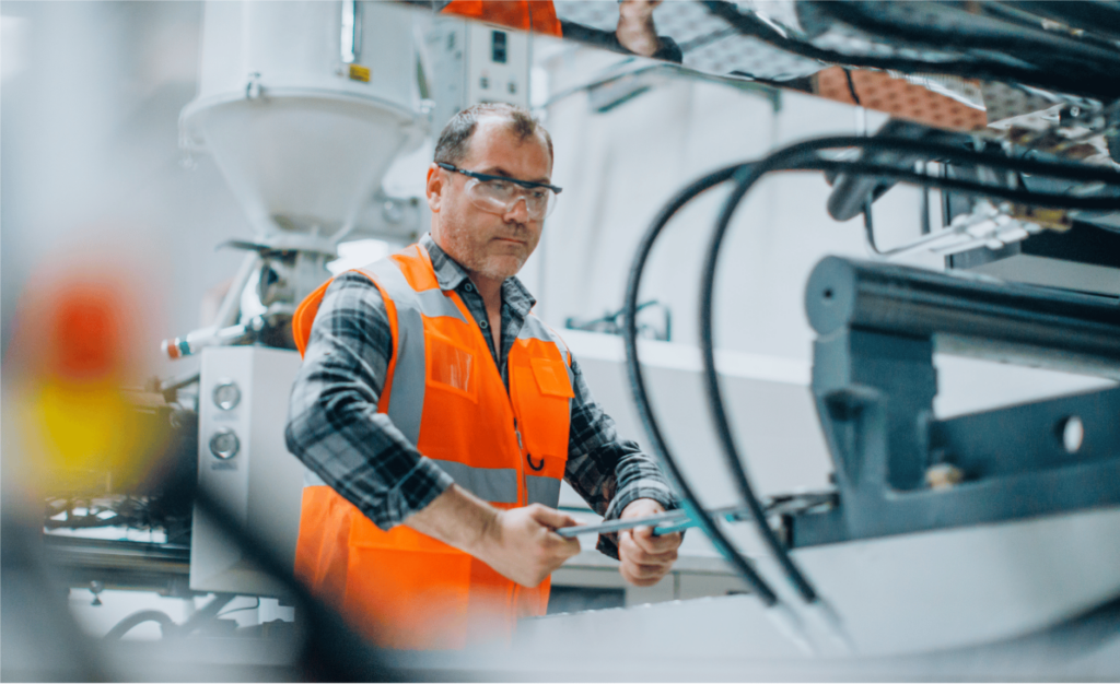 Close up shot of man in a safety vest working at a machine in a factory