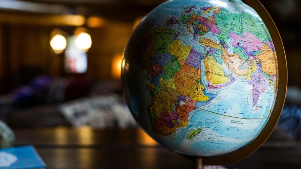 A close up of a globe on a desk. Room blurred out in background. Africa, Europe, Middle East are all visible on the globe.