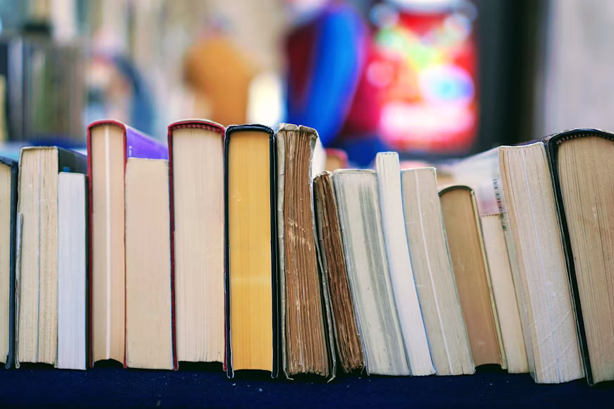 image of a stack of random books with a nod toward the article summer reading list